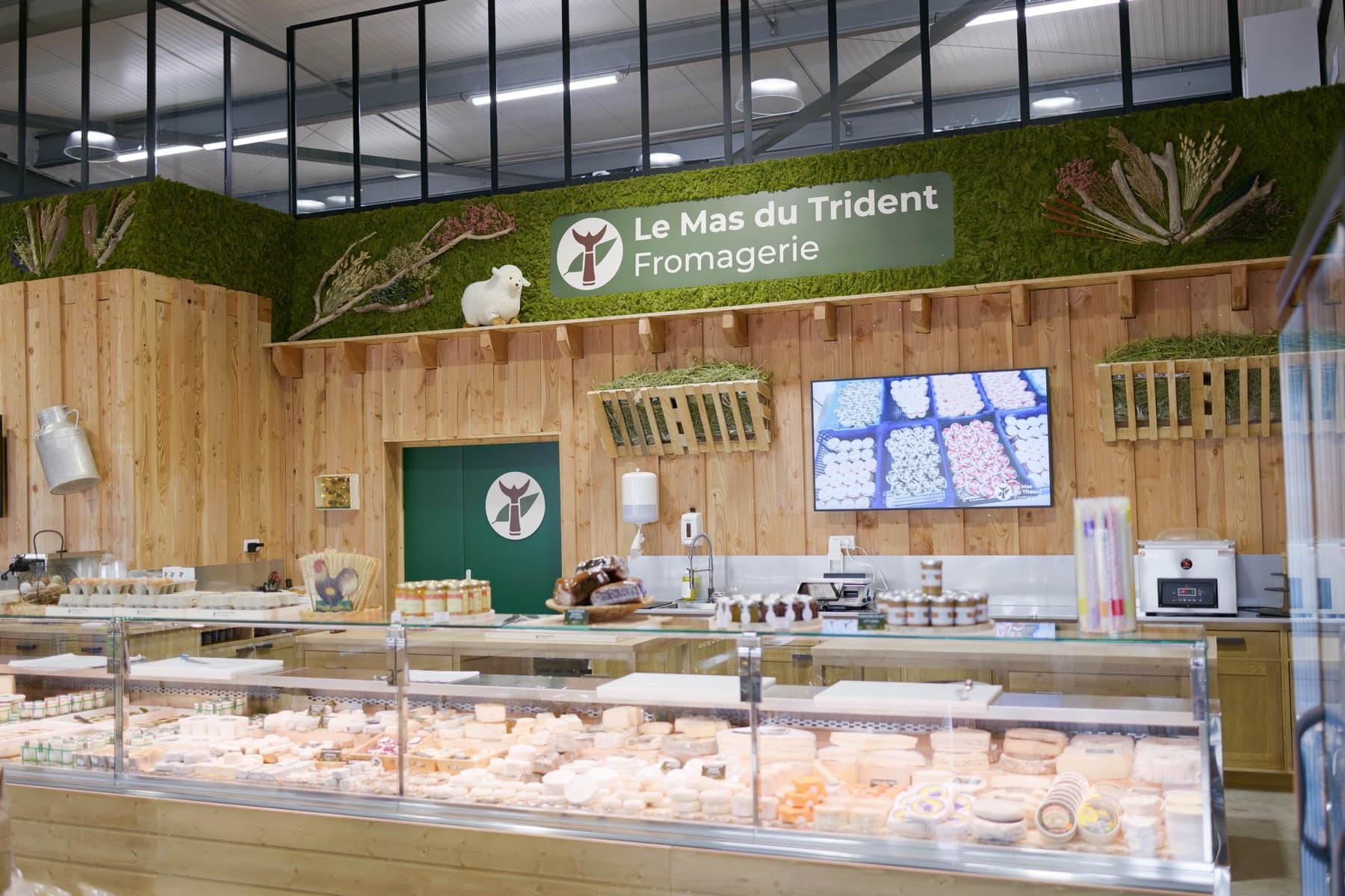 La banque de fromages de notre boutique de Saint-Dionisy sous l'enseigne Le Mas du Trident, vitrine pleine et écriteaux posés