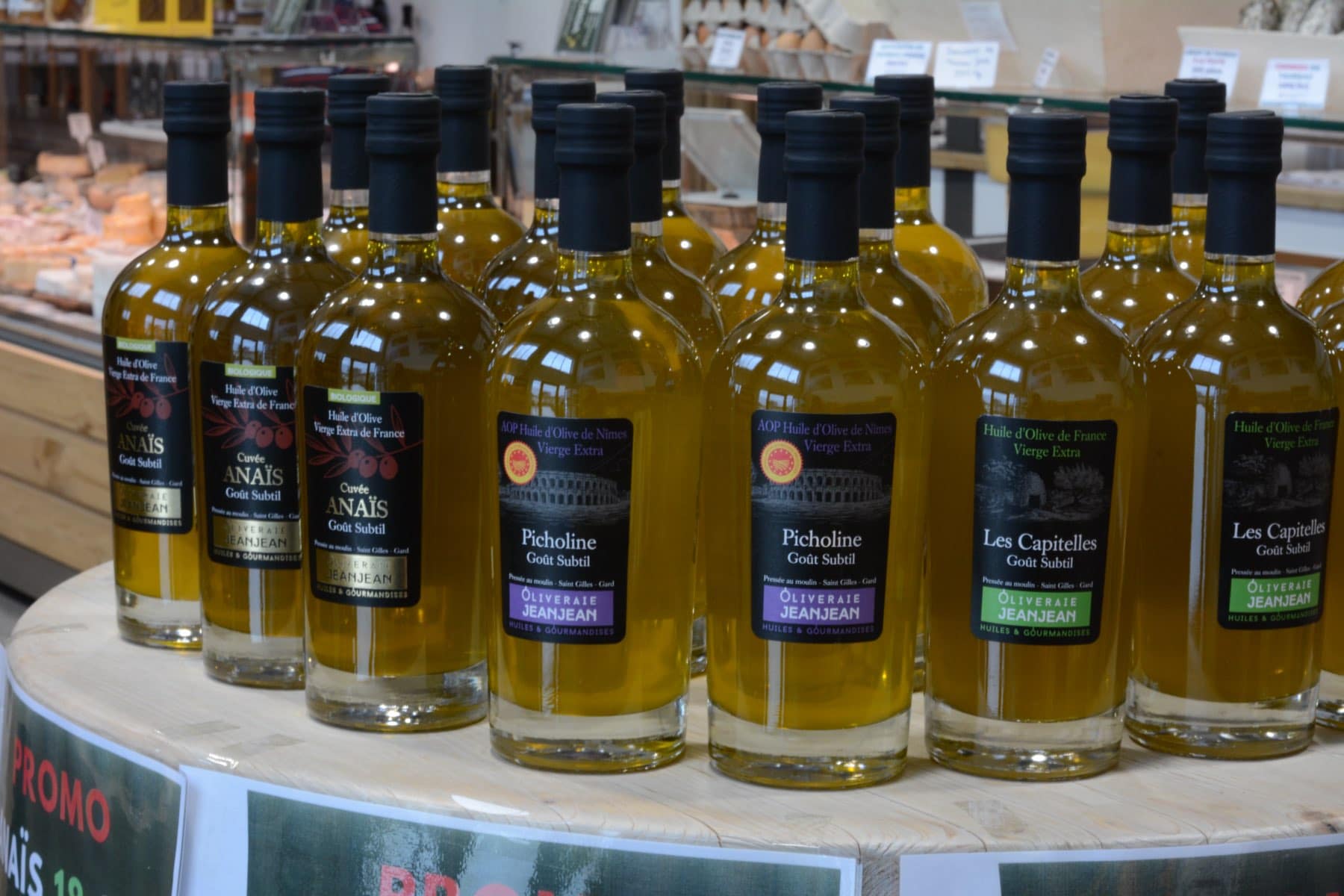 Bouteilles d'huile d'olive locale en promotion sur un présentoir de notre boutique, devant la banque de coupe