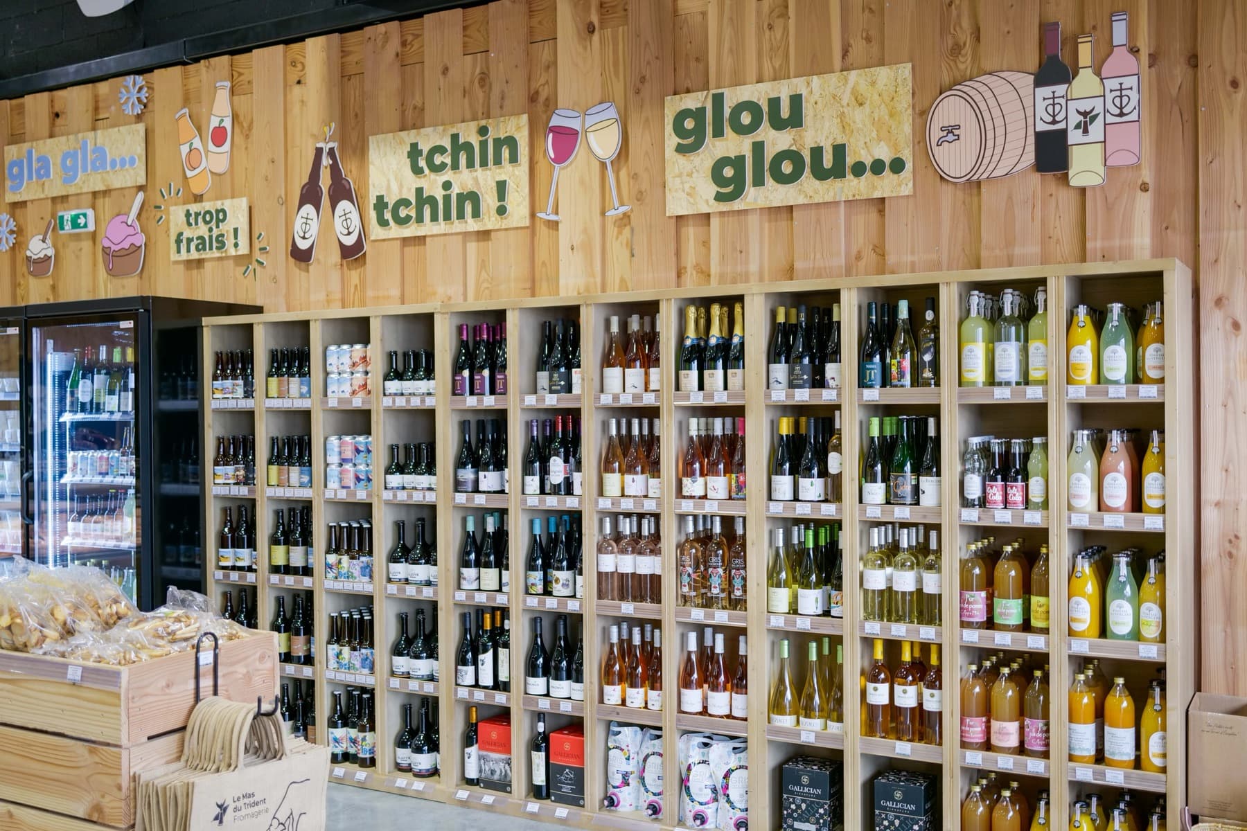 La cave de la boutique de Saint-Dionisy : rayons de vins, rosés et bières, chaque bouteille avec son étiquette de prix