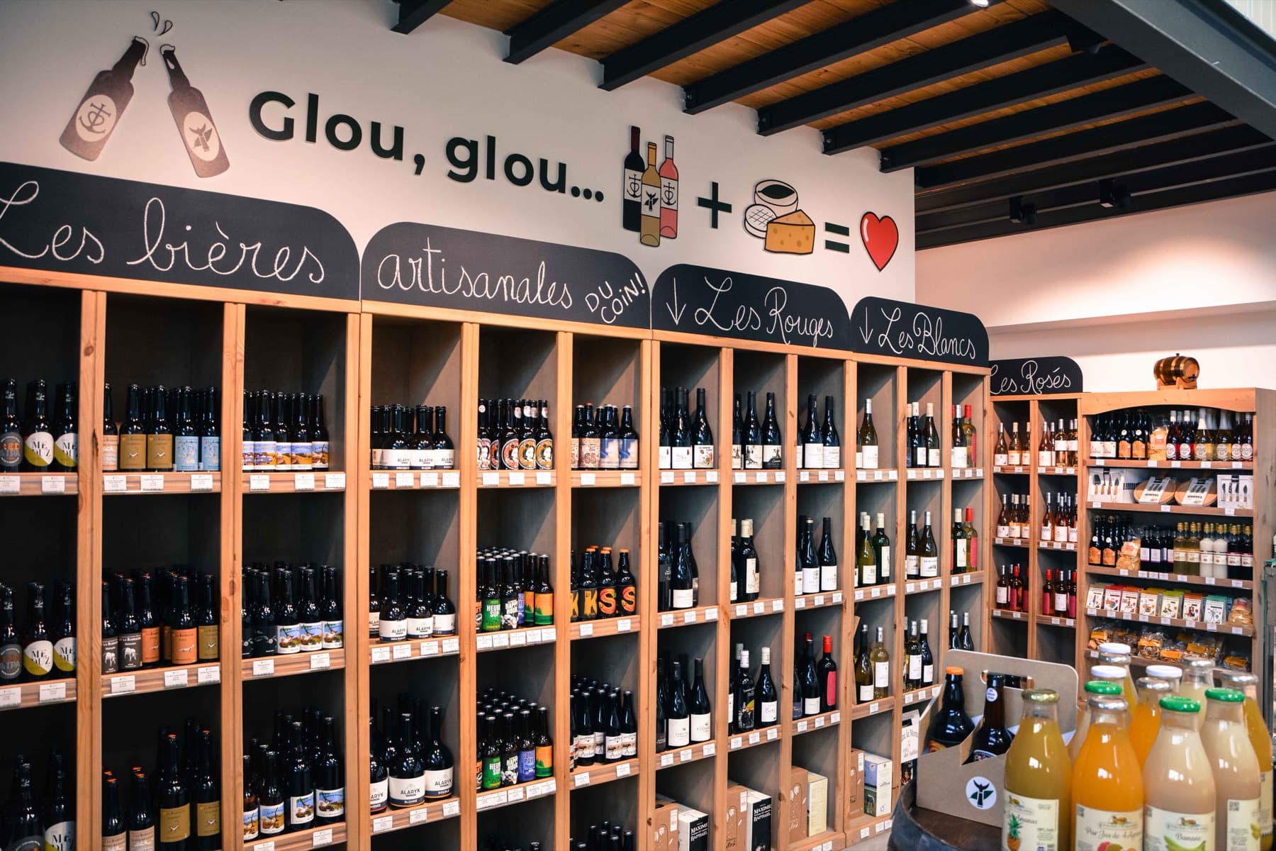 La cave du Mas du Trident à Vauvert : rayonnages de vins de vignerons, bières artisanales et jus, avec les étiquettes de prix posées en rayon